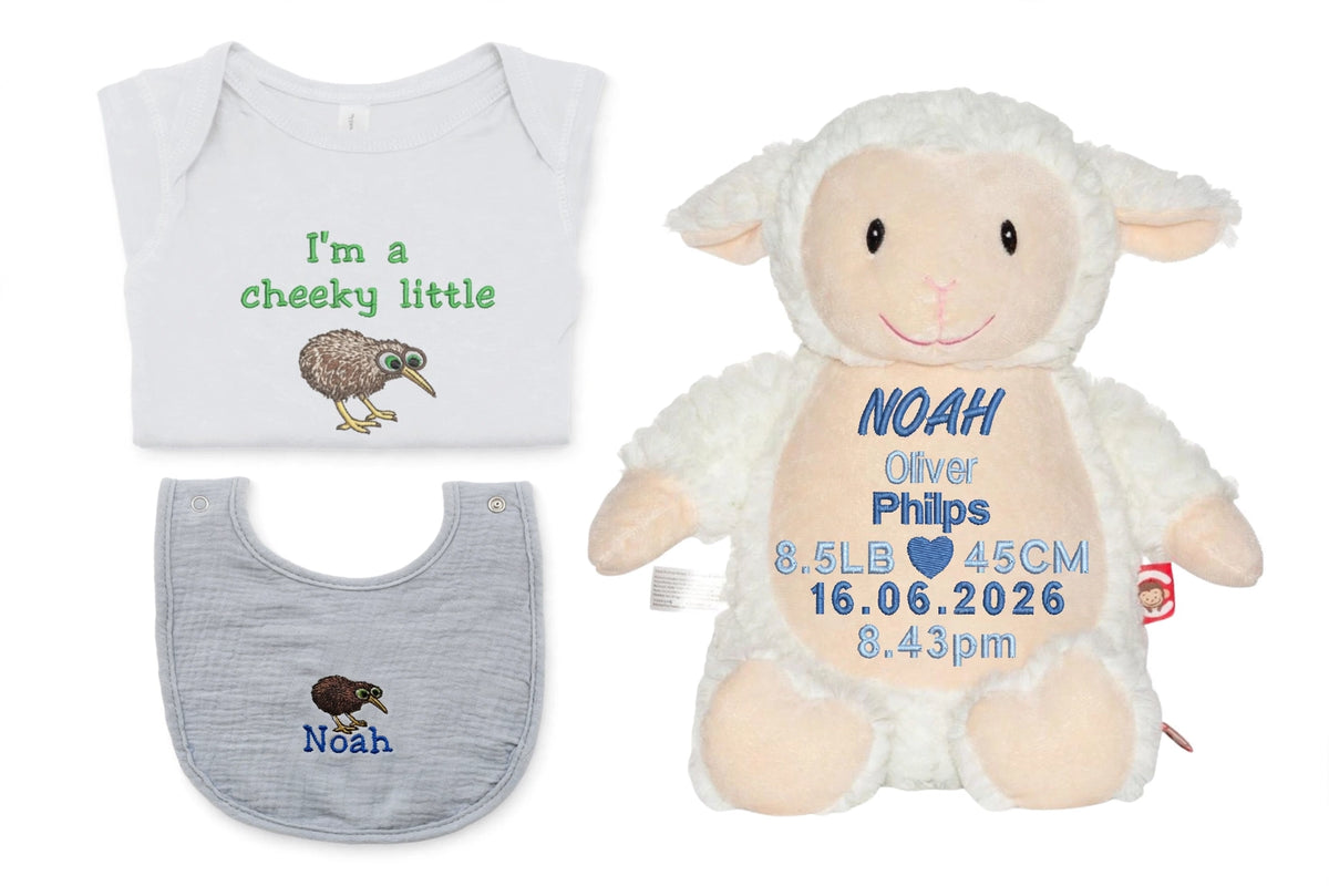A personalized baby gift set featuring a white short-sleeve bodysuit with green text and a kiwi bird graphic, a gray muslin bib with a kiwi bird design, and a plush white lamb toy with custom blue text.