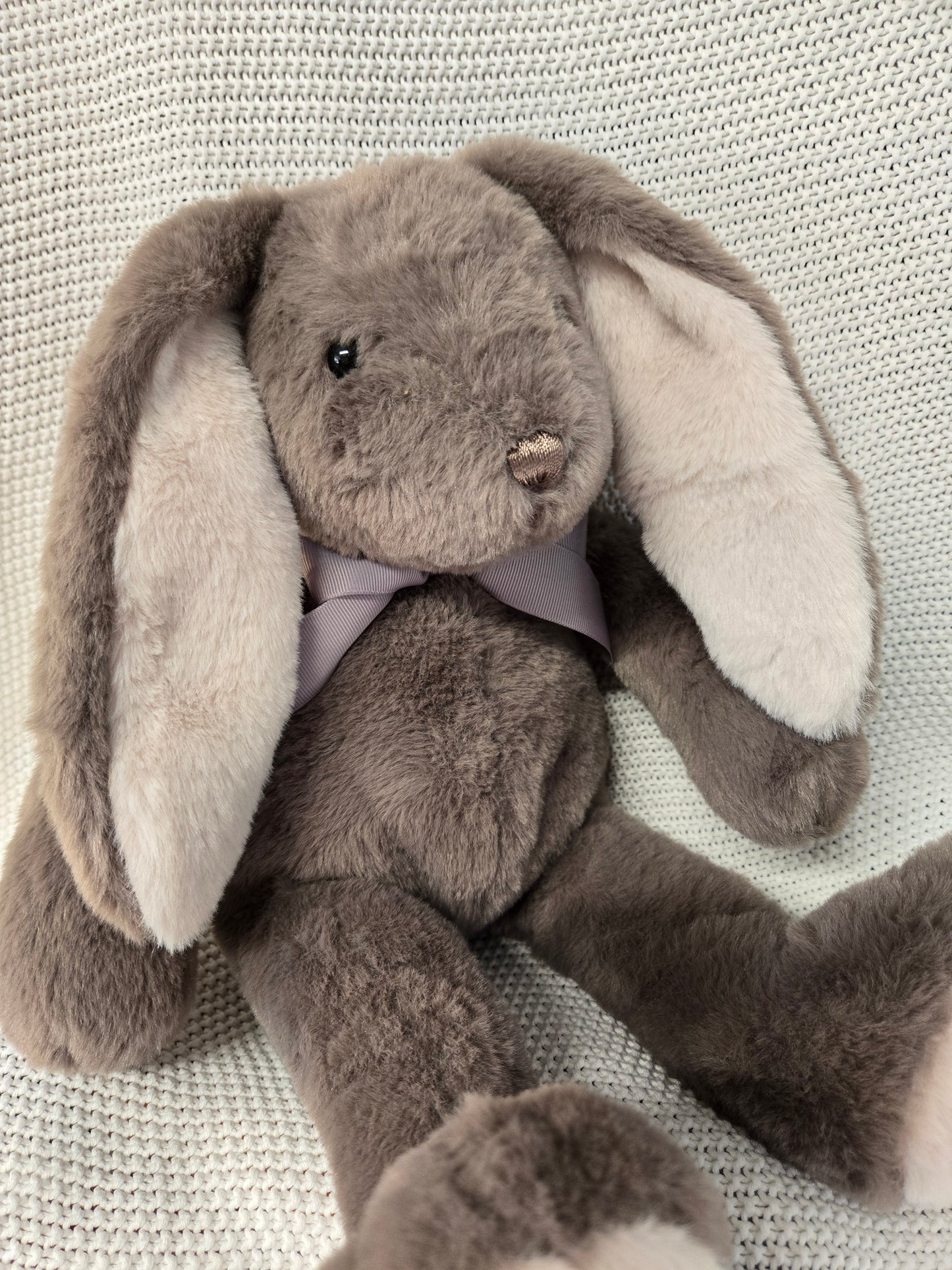 Plush toy resembling a snake with a gray and white color scheme on a textured surface.