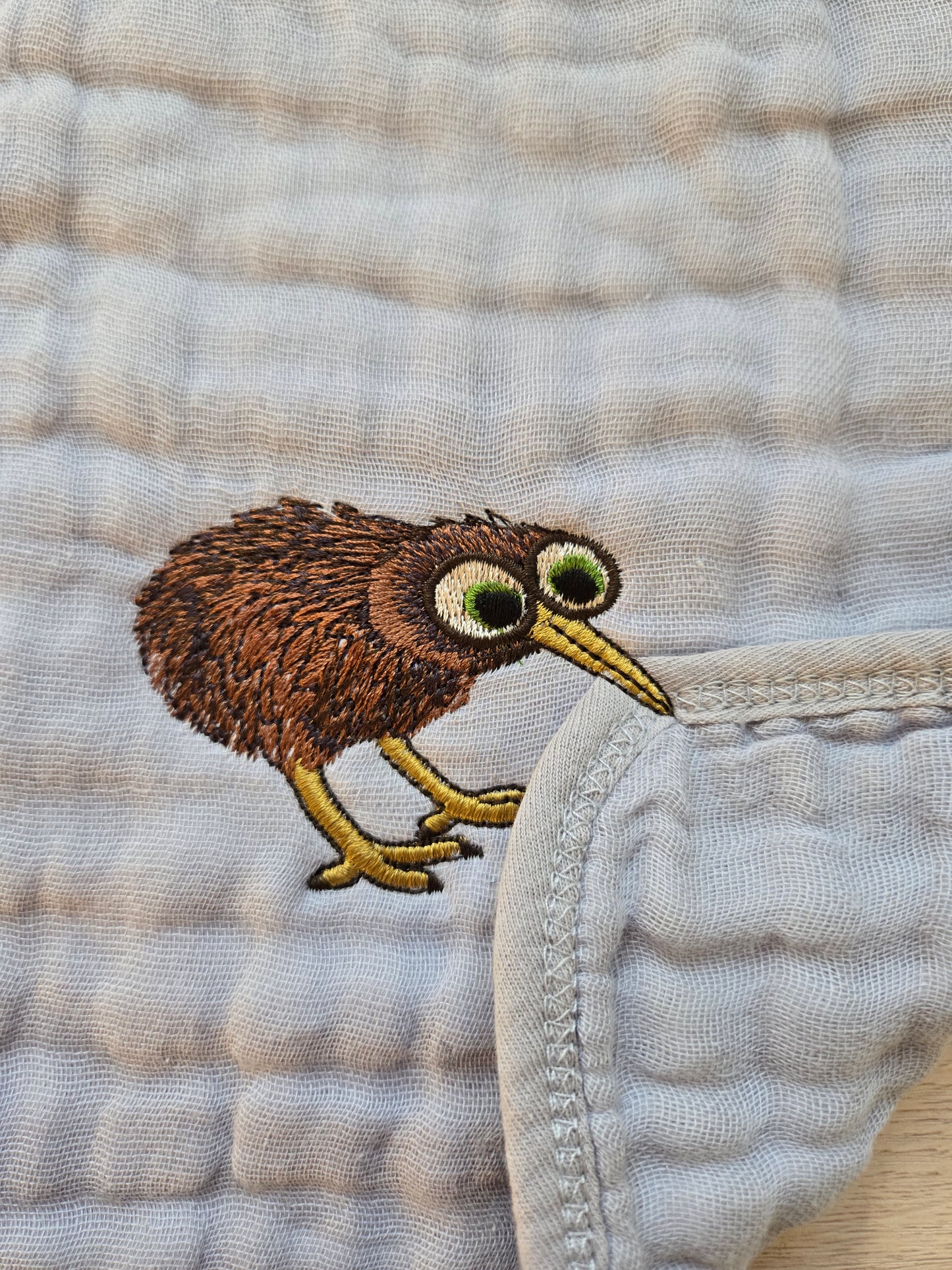 Embroidered kiwi bird on a textured fabric background