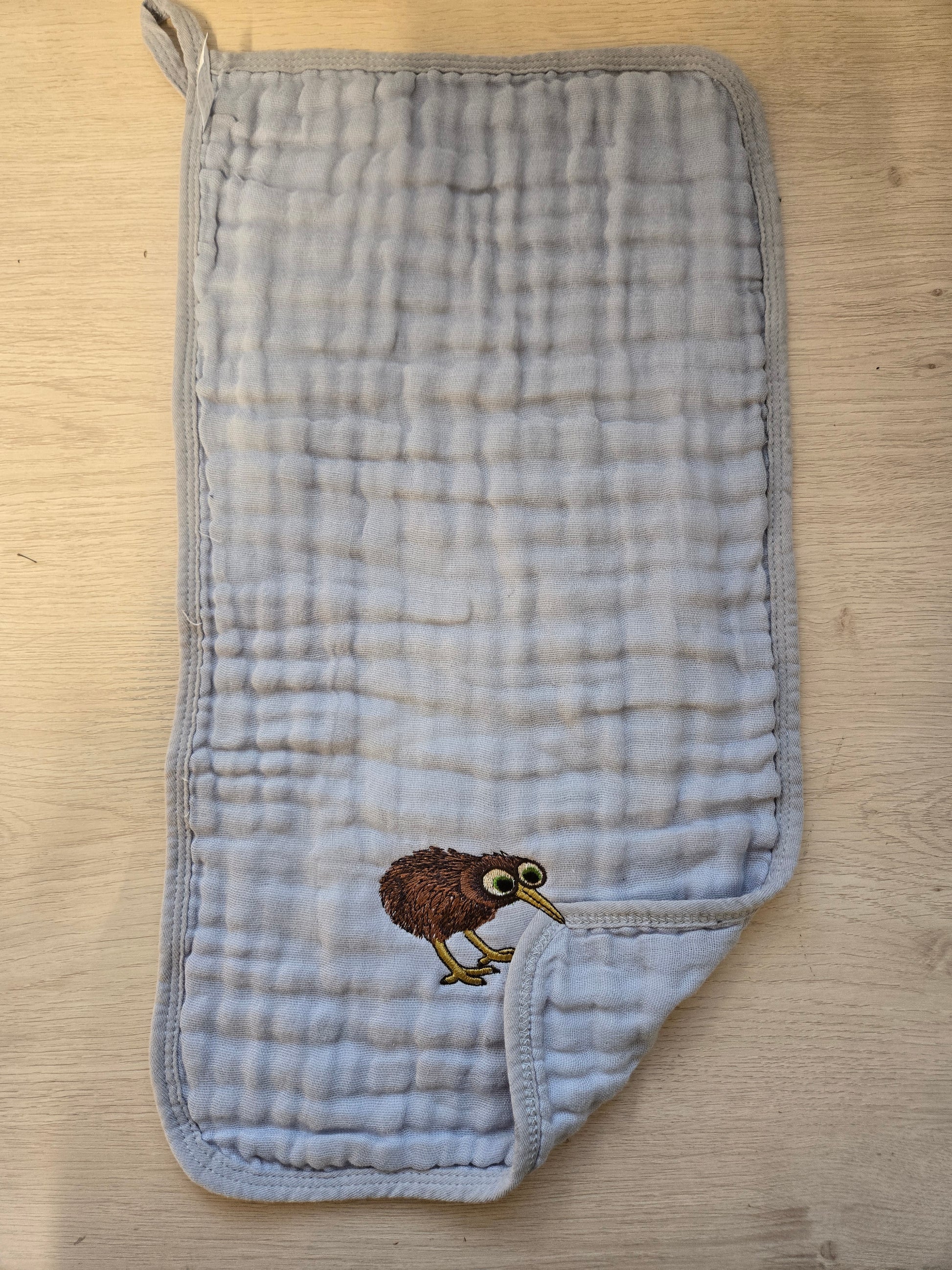 Embroidered kiwi bird pet thief tea towel hanging on a country style kitchen oven handle, made in NZ.