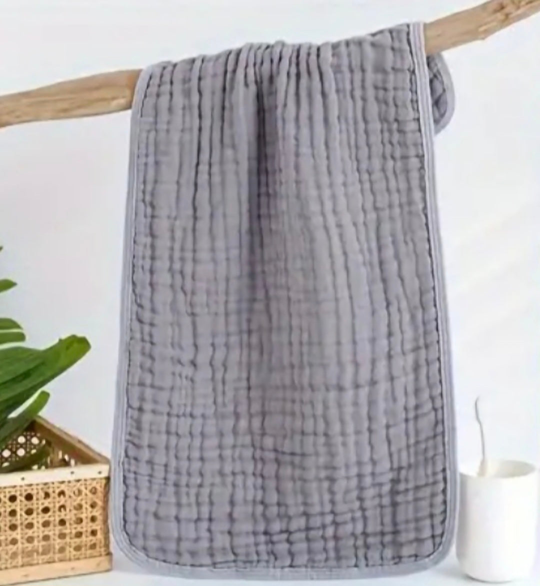 Gray textured towel hanging on a wooden rack with a white background
