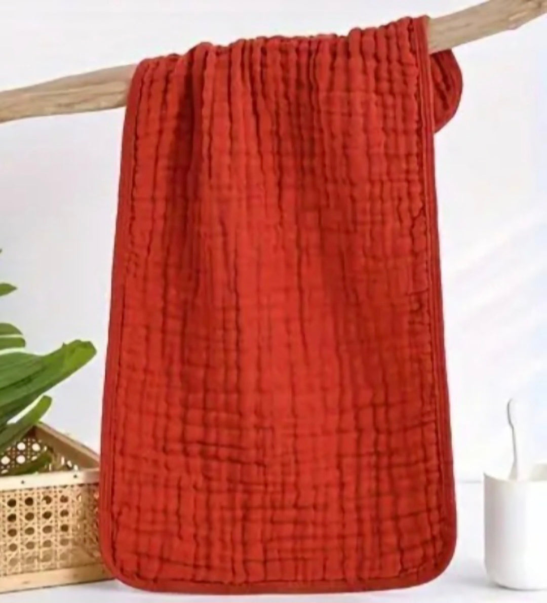 Red textured blanket draped over a wooden stick with a white background