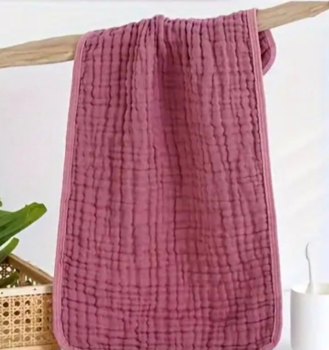 Rose textured towel hanging on a wooden rack with a white background