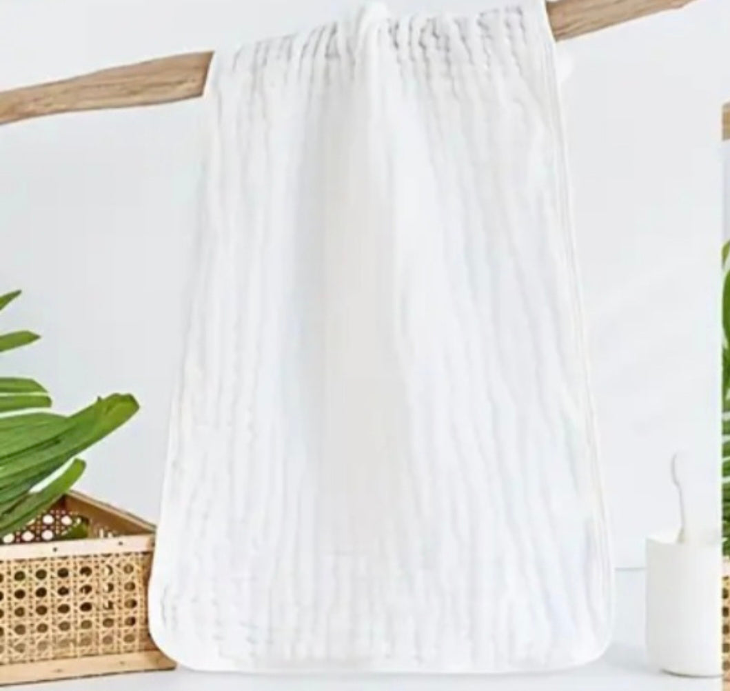 White towel hanging on a wooden rack with green plants in the background