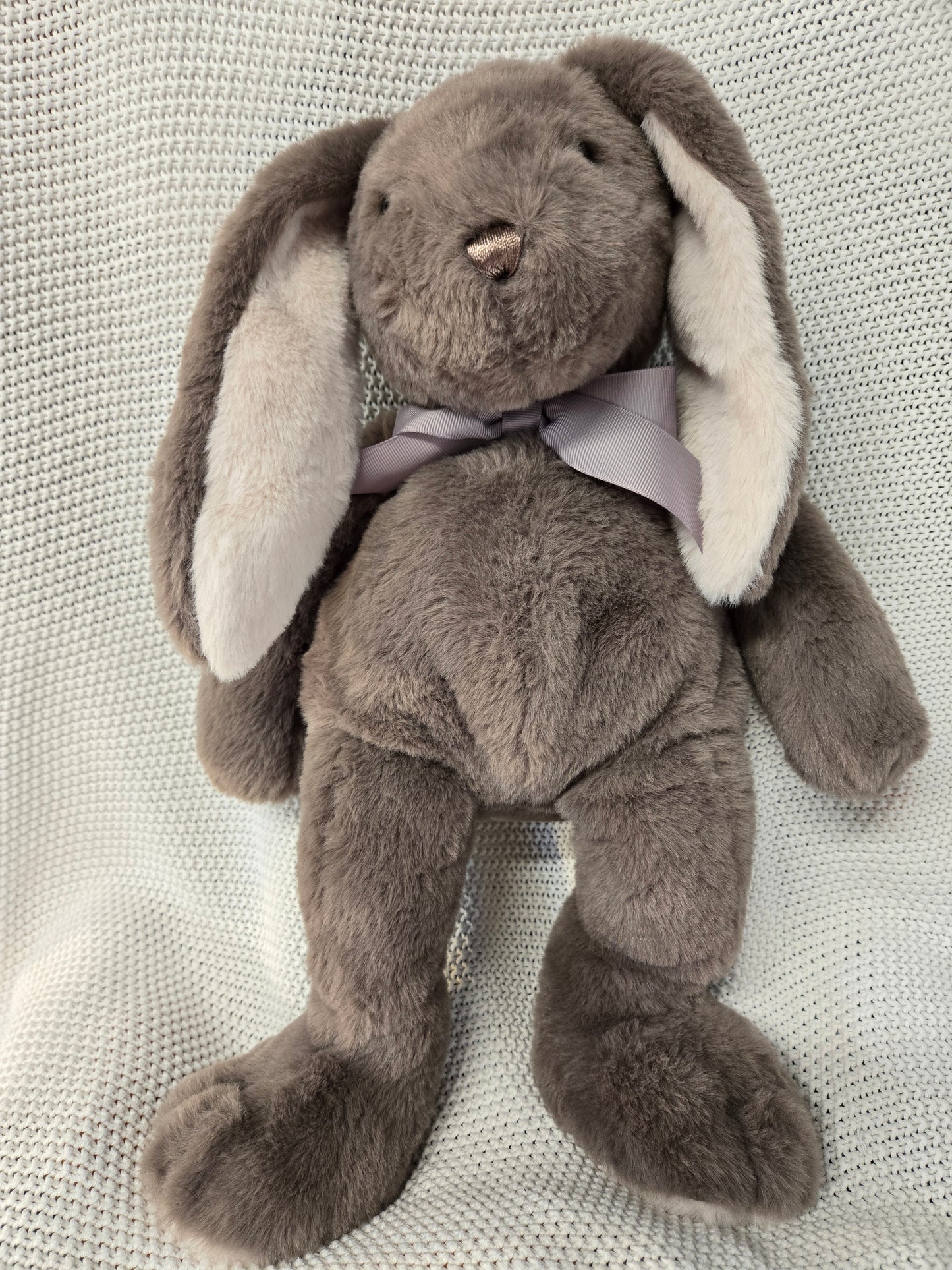 Plush bunny toy with a bow tie on a textured fabric background