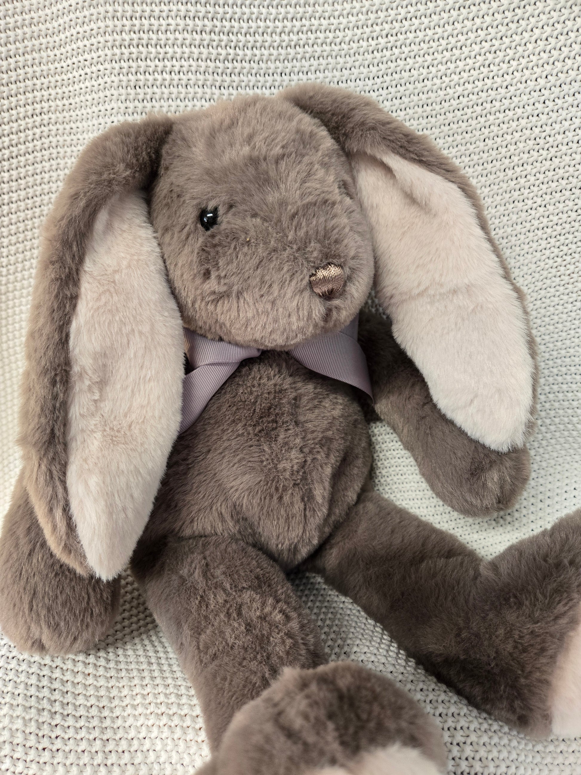Plush toy resembling a snake with a gray and white color scheme on a textured surface.